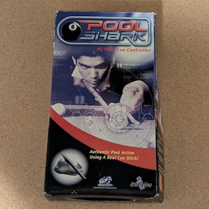 May include: A rectangular product box for a Pool Shark PC pool cue controller. The box features a blue and black design with an image of a person using a pool cue. Text on the box reads Pool Shark, PC Pool Cue Controller, and Authentic Pool Action.