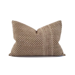 May include: A rectangular decorative pillow with a brown and beige geometric pattern. The pillow features a central vertical stripe with a detailed zigzag design, adding a textural contrast to the overall aesthetic. The pillow is designed for home decor.