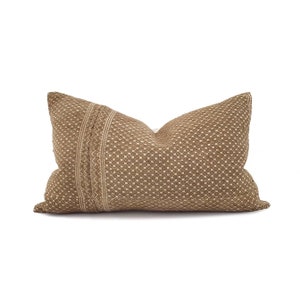 May include: A rectangular decorative pillow with a woven texture in shades of brown and beige. The pillow features a repeating square pattern and a vertical stripe with a zig-zag design. The pillow is designed for home decor.