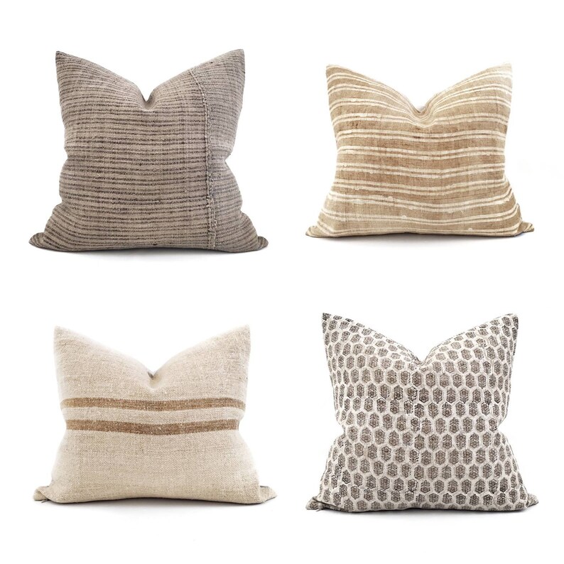 Puede incluir: Cuatro cojines decorativos en tonos neutros. Los cojines presentan diversas texturas y patrones, incluyendo rayas, un dise&ntilde;o de panal y tejidos. La paleta de colores incluye beige, marr&oacute;n y gris.
