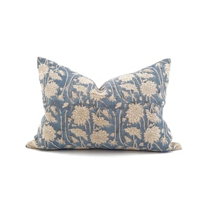 May include: A decorative pillow with a blue background and a beige floral pattern. The pillow has a rectangular shape and is designed for home decor. The floral design is a repeating pattern of stylized flowers and leaves.