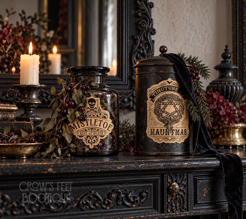 Pu&ograve; includere: Un barattolo di vetro trasparente etichettato MISTLETOE KISS OF DEATH con un'icona a teschio e un contenitore in metallo nero etichettato TINCTURE OF HAUNTMAS con un disegno a pentagramma. Entrambi sono decorati con fogliame scuro e bacche.