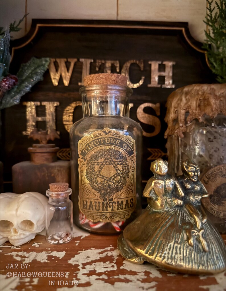 Pu&ograve; includere: Un barattolo da farmacia in vetro trasparente con tappo in sughero, dotato di un'etichetta dorata con la scritta Tincture of Hauntmas, riempito di piccoli bastoncini di zucchero. Il barattolo &egrave; circondato da una statuetta in ottone e un teschio.