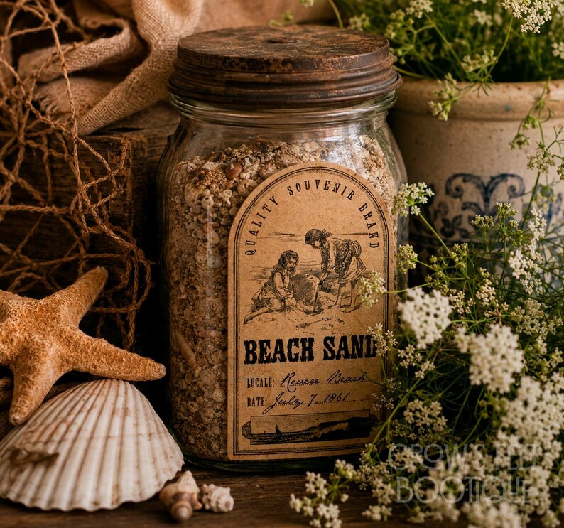 Op de afbeelding: Een glazen pot gevuld met strandzand, afgesloten met een donker, verweerd metalen deksel. De pot is voorzien van een vintage-stijl etiket met de tekst Quality Souvenir Brand, Beach Sand, Locale: Revere Beach en Date: July 7, 1861, met illustratie.
