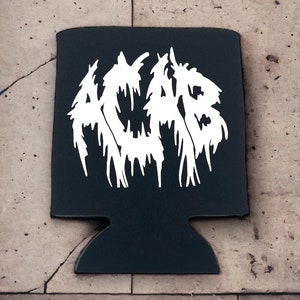May include: Black drinks cooler featuring the white letters "ACAB" in a dripping font. The cooler has a cutout for a can and is set against a textured, light-coloured surface.