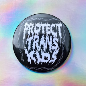 May include: Black and white button with the text "PROTECT TRANS KIDS" in a bold, stylized font surrounded by a chain link design.