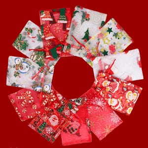May include: A circular arrangement of small, square Christmas gift bags on a red background. The bags display festive patterns including Christmas trees, snowmen, and Santa Claus, with red drawstrings.