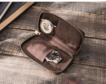 May include: A brown leather watch case with two watches inside. The case has a zipper closure and is lined with brown felt. The watches are both silver and gold toned.