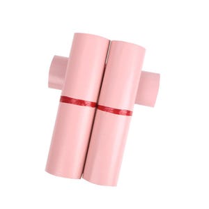 May include: Several pink mailing envelopes are bundled together, secured with red tape. The envelopes are cylindrical in shape and appear to be made of a durable material. The background is plain white.