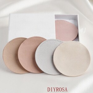 May include: Set of four round suede coasters in beige, light pink, gray, and a darker pink. The coasters are in a white box with the word "DIYROSA" printed on the bottom.