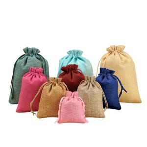 Könnte beinhalten: Sortiment von zehn kleinen Kordelbeuteln aus Jutegewebe in verschiedenen Farben, darunter Grün, Blau, Rot, Rosa und Braun. Die Beutel eignen sich ideal zum Verpacken von kleinen Geschenken oder Mitbringseln.
