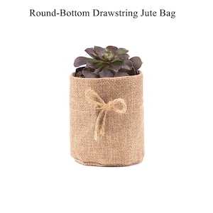 Puede incluir: Una bolsa de yute de fondo redondo con cordón, que contiene una planta suculenta. La bolsa está hecha de un material natural tejido y atada con un lazo de yute. El texto "Round-Bottom Drawstring Jute Bag" está en la parte superior.