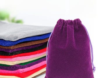 Pode incluir: Um conjunto de sacos de veludo com cordão de cor roxa, vermelha, marrom, bege, verde e azul. Os sacos são feitos de um tecido macio e luxuoso e são perfeitos para guardar pequenos objetos como joias, presentes ou lembrancinhas.