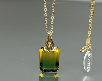 Può includere: Una collana con catena d'oro con un ciondolo di pietra preziosa verde e gialla. Il ciondolo è di forma quadrata con una parte superiore appuntita. La catena è delicata e ha una piccola chiusura.