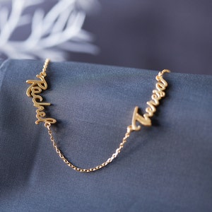 May include: A gold necklace with two names, "Rachel" and "Trevor", written in cursive script.