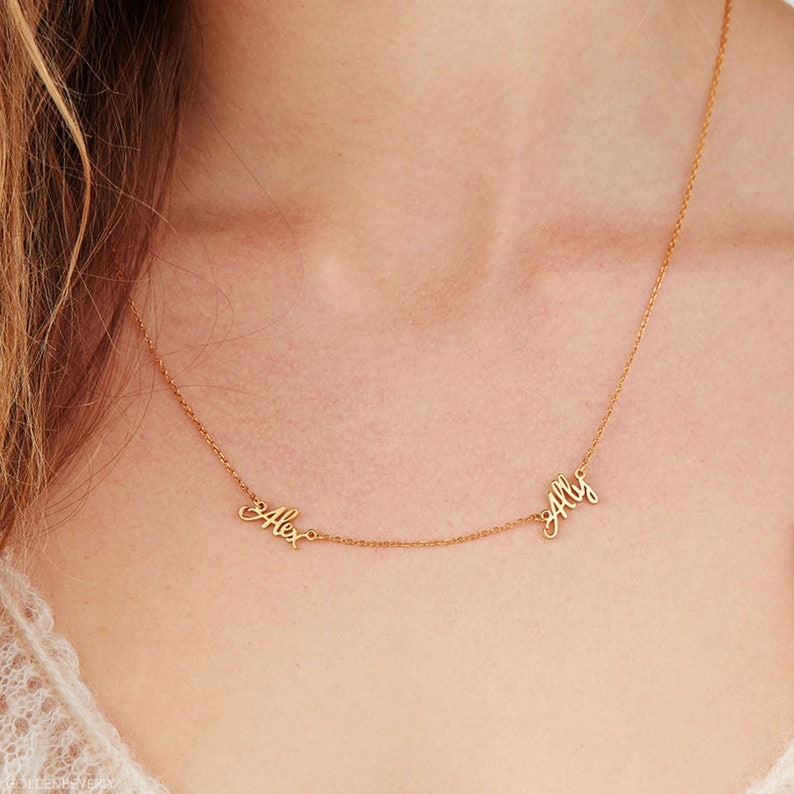 Op de afbeelding: Gouden ketting met twee namen, "Alex" en "Ally", geschreven in cursief.