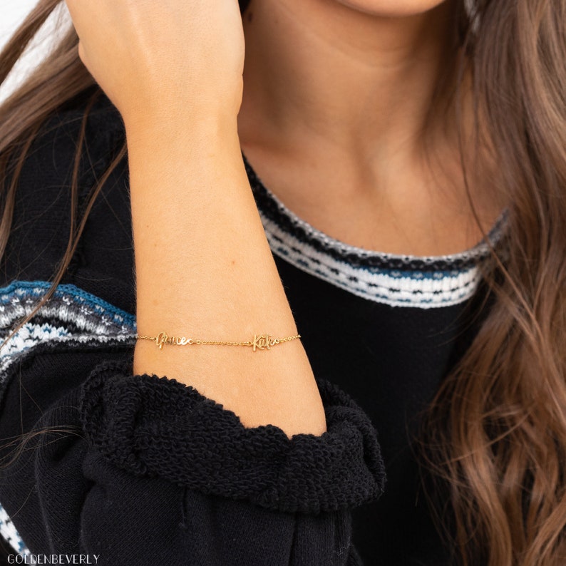 K&ouml;nnte beinhalten: Goldkette Armband mit den Namen "Anne" und "Kate" in Kursivschrift.