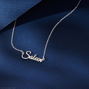 Op de afbeelding: Een zilveren ketting met de naam "Saleen" in cursief schrift.