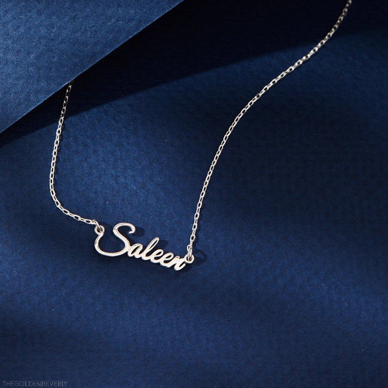 Op de afbeelding: Een zilveren ketting met de naam "Saleen" in cursief schrift.