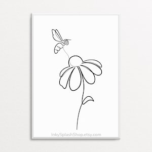 May include: Black and white line art print of a bee hovering over a daisy. The minimalist design features a single continuous line forming the bee, flower, stem, and leaves. The print is framed in a white border and includes the website address InkySplashShop.etsy.com.