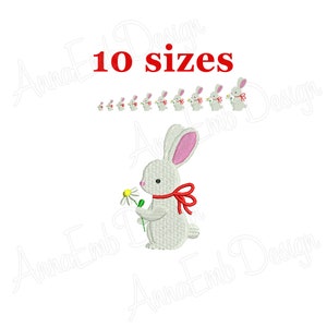 May include: White bunny holding a daisy with a red bow around its neck. 10 sizes of the bunny are shown in a row above the main image.