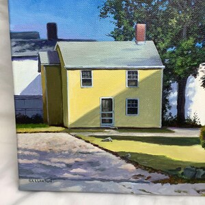 May include: A painting of a yellow house with a white door and windows. The house is surrounded by green grass and a blue sky. The painting is signed "C.LLAWTON".