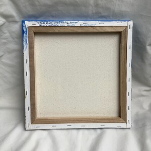 May include: A close-up of the back of a stretched canvas painting. The canvas is white and the frame is made of wood. The painting is titled "19 Jenks Street - Central Falls RI 9:09 am" and is signed "Lourive Lynn Lowton 2025 Acrylic" with the social media handle "@triplelstudioart" in the bottom right corner.