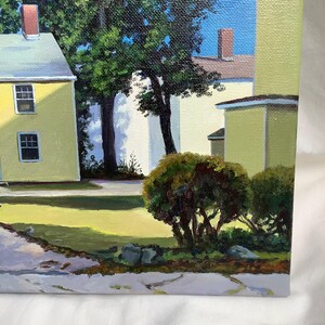 May include: A painting of a yellow house with a green roof and a white house in the background. There are trees and bushes in the foreground.