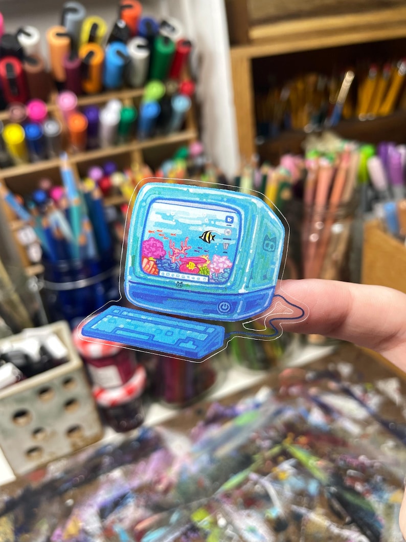 Peut inclure: Autocollant transparent repr&eacute;sentant un ordinateur r&eacute;tro avec une sc&egrave;ne d'aquarium &agrave; l'int&eacute;rieur du moniteur. L'autocollant a un clavier et un moniteur bleus, avec un poisson noir et jaune, du corail et d'autres cr&eacute;atures aquatiques.
