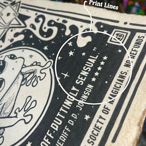 May include: Black and white illustration of a frog with the text "OFF-DUTTINGLY SENSUAL." SHERIFF D.D. JOHNSON ★  BY THE SOCIETY OF MAGICIANS. NO REFUNDS.