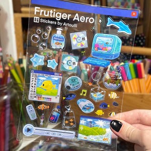 Peut inclure: Une planche d'autocollants transparente avec des motifs Frutiger Aero. Les autocollants comprennent un ordinateur r&eacute;tro, des CD, des poissons, des bulles et un bouton de lecture. Le texte "Frutiger Aero Stickers by Artoulli" est imprim&eacute; en haut.