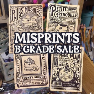 May include: Four vintage-style cards featuring illustrations of frogs with text overlays. The cards are printed on a textured, beige paper. The text on the cards includes "Phibs Mushis", "Petite Grenouille", "For County Sheriff", and "Magic Man".