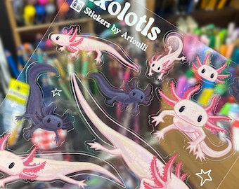 May include: A clear sticker sheet featuring multiple illustrations of pink and dark purple axolotls in various poses, accompanied by small white star outlines. The text Axolotls Stickers by Artoulli is printed in white at the top.