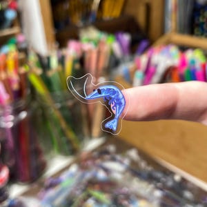 May include: A small, die-cut sticker featuring a blue shrimp illustration with a clear border. The shrimp is depicted in a curled position with a dark eye and detailed shading, showcasing a vibrant blue color palette against a transparent background.