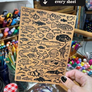May include: A rectangular tan sheet of paper featuring a dense collection of black ink illustrations of various fish species. The top of the sheet includes a black banner with the white text "Bonus print with every sheet" and a downward arrow.