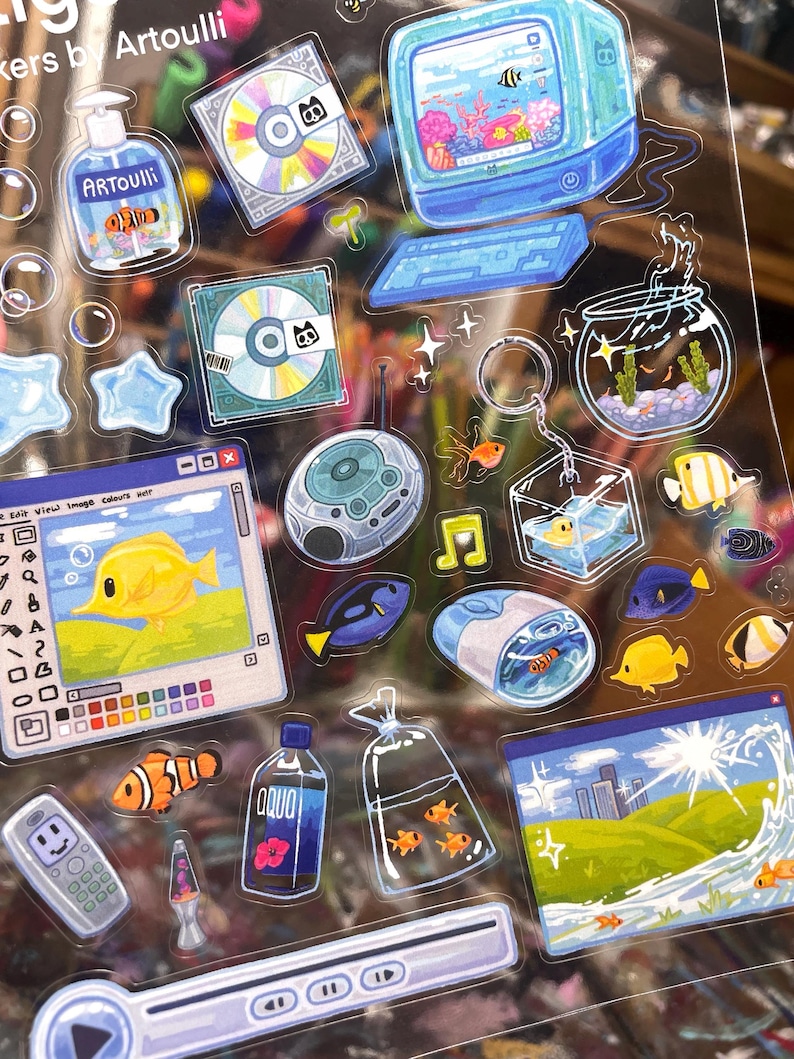 Peut inclure: Une planche d'autocollants color&eacute;s repr&eacute;sentant la vie aquatique et la technologie r&eacute;tro. Les motifs comprennent un ordinateur, des CD, un aquarium, une lampe &agrave; lave et une bouteille avec l'inscription "AQUO". Les autocollants ont une finition brillante et sont de formes vari&eacute;es.