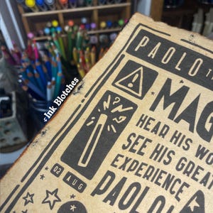 May include: A vintage-style poster with a black and white illustration of a magic wand and stars. The text on the poster reads "PAOLO! MAGIC HEAR HIS WORDS SEE HIS GREAT EXPERIENCE PAOLO!" and "02 AUG".