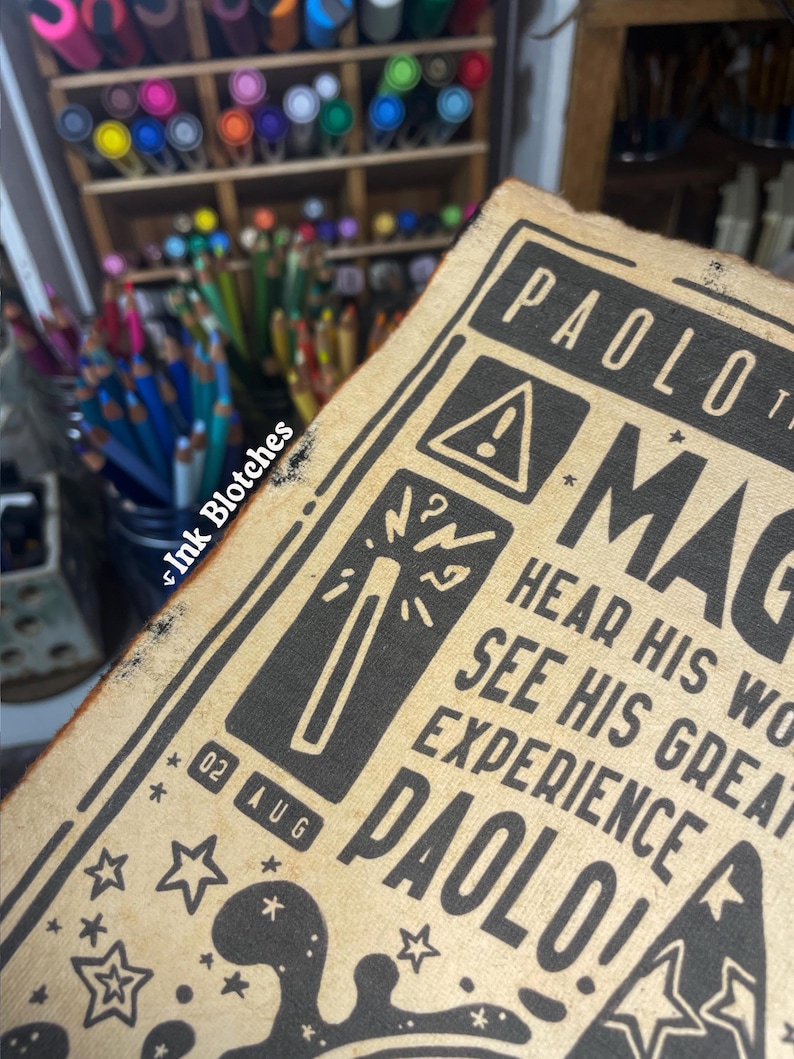 May include: A vintage-style poster with a black and white illustration of a magic wand and stars. The text on the poster reads "PAOLO! MAGIC HEAR HIS WORDS SEE HIS GREAT EXPERIENCE PAOLO!" and "02 AUG".