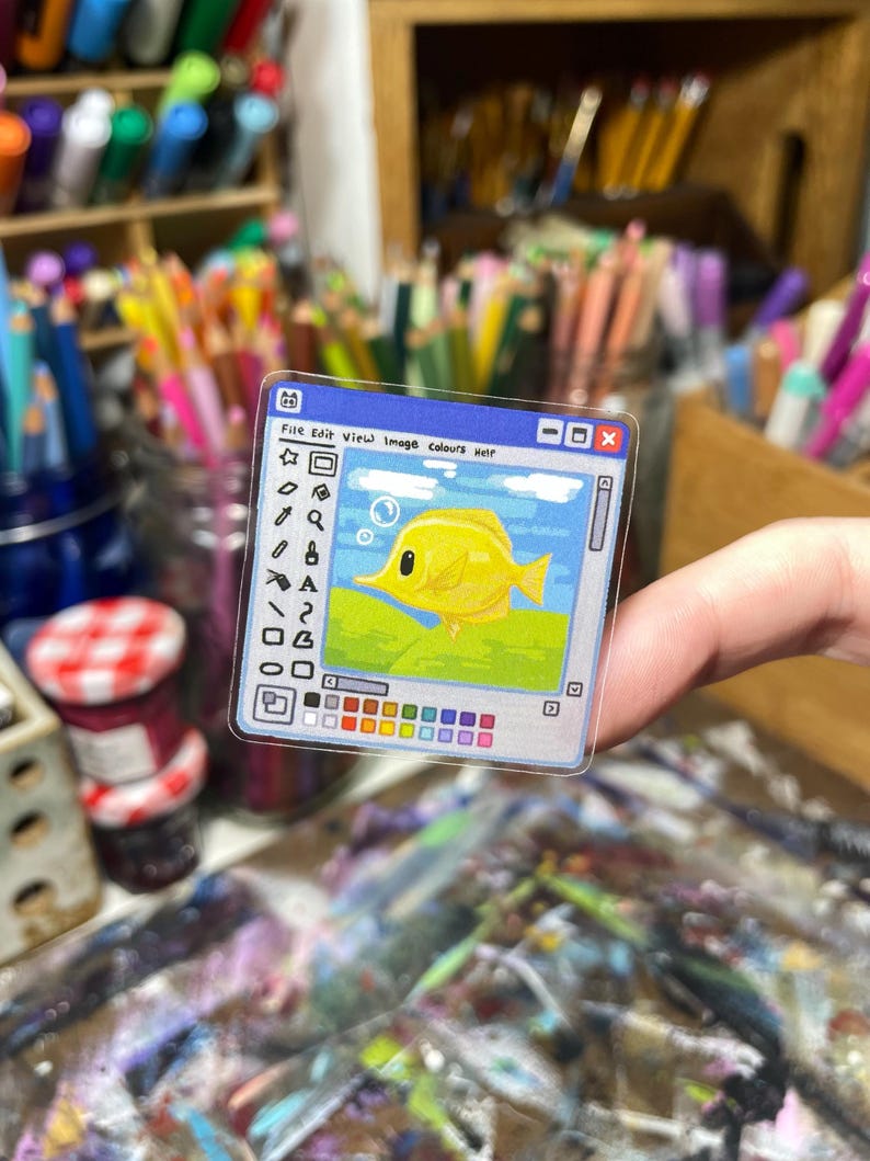Peut inclure: Un autocollant transparent repr&eacute;sentant un poisson jaune dans un cadre de fen&ecirc;tre bleu, rappelant une interface informatique. L'autocollant comprend le texte "File Edit View Image Colours Help" et une palette de couleurs.