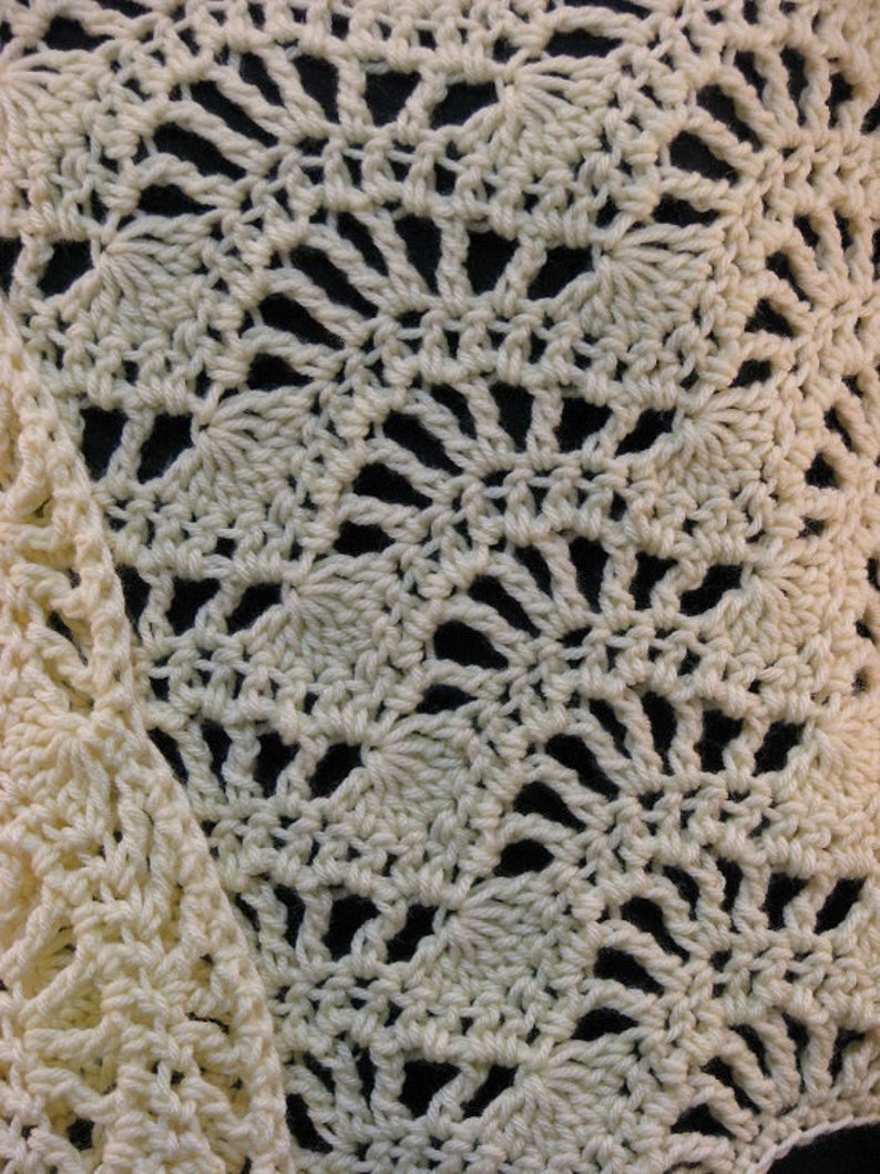 May include: Close-up of a crocheted fabric with a delicate, lacy pattern in a cream color.