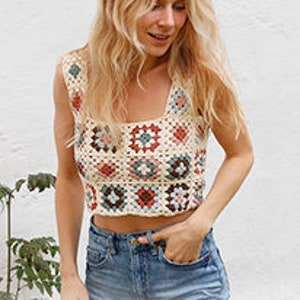 Peut inclure: Un top en crochet sans manches avec un motif carré dans des tons beige, marron, rouge et bleu. Le haut a un décolleté carré.