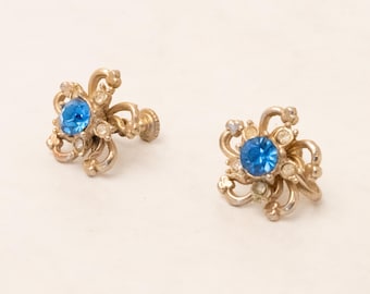 Pendientes dorados con forma floral y cierre de rosca, con cristales azules y transparentes, década de 1960.