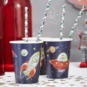 May include: Set of blue and red paper cups with a space theme. The cups feature a rocket, a UFO, planets, and stars. The cups are perfect for a space-themed party.