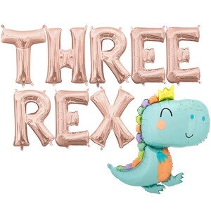 May include: Rose gold foil balloons spelling "THREE REX" with a blue dinosaur balloon with a crown.