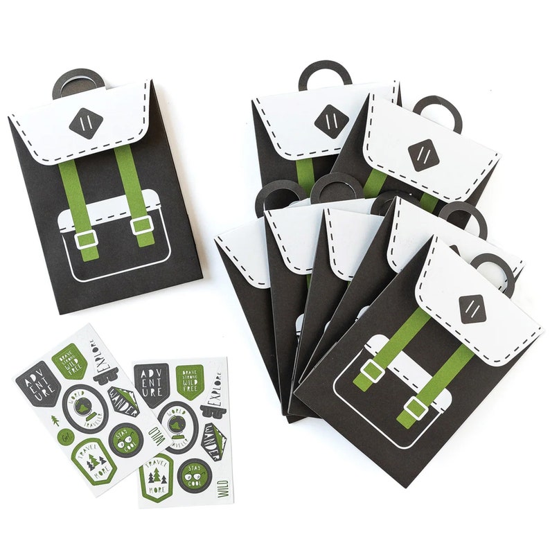 May include: Set of eight black and white paper favour bags with a green backpack design. Each bag has a white flap with a small black rectangle and the number "11" inside. The bags are accompanied by a sheet of stickers with various designs, including a compass, a globe, and a mountain.