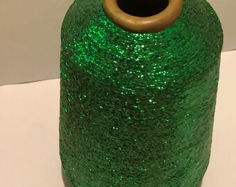 May include: A spool of green glitter yarn with a brown cardboard center.