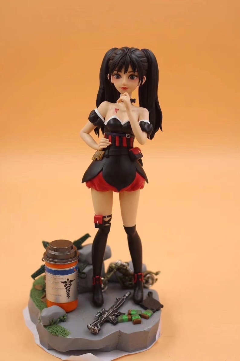 K&ouml;nnte beinhalten: Detaillierte Figur eines weiblichen Anime-Charakters in einem schwarz-roten Outfit mit Z&ouml;pfen. Die Figur steht auf einem Sockel mit einem medizinischen Beh&auml;lter, einem Gewehr und anderem Zubeh&ouml;r. Der Hintergrund ist einfarbig orange.