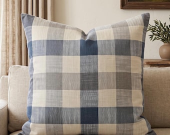 Könnte beinhalten: Ein quadratisches Zierkissen mit einem großflächigen Karomuster in Marineblau, Schiefergrau und Off-White. Der Stoff weist eine sichtbare Webstruktur auf und das Kissen ist prall gefüllt, um eine strukturierte quadratische Form beizubehalten.