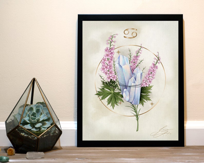May include: A watercolour illustration of the Cancer zodiac sign with a gold symbol and a circle around a cluster of blue crystals and pink flowers.