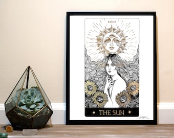 Puede incluir: Una ilustración en blanco y negro de la carta del Sol del tarot. La carta presenta a una mujer con el pelo largo y suelto y un sol con tres ojos sobre su cabeza. La carta está enmarcada en negro y tiene detalles dorados.